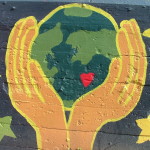 Mural of hands holding a green Earth with a heart in it.